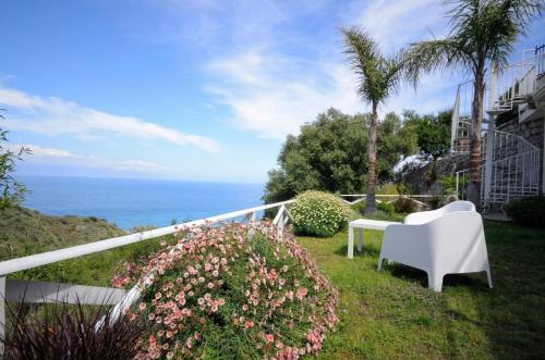 un balcón con una silla blanca, flores y el océano en Ferienwohnung für 4 Personen ca 45 qm in Taormina, Sizilien Ostküste von Sizilien - b57254, en Taormina