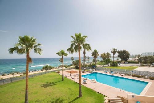 una piscina con palmeras y el océano en Ferienwohnung für 7 Personen ca 90 qm in Protaras, Südküste von Zypern en Protaras