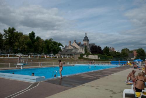a woman in a bikini standing next to a swimming pool at Spacieuse maison de village in Luché-Pringé