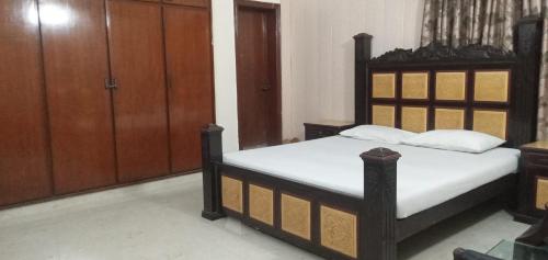 - une chambre avec un lit doté de draps blancs et de placards en bois dans l'établissement Decent Palace, à Lahore