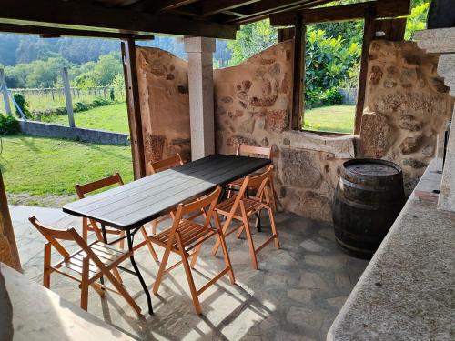 a wooden table and chairs on a patio with a barrel at Casa turística a Ardiña in Caldas de Reis