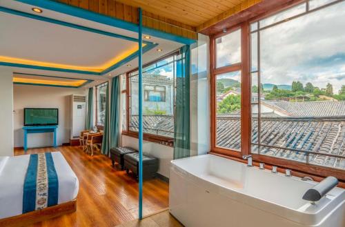1 dormitorio con bañera y ventana grande en Dream Tour Scenic Inn 梦之旅观景客栈, en Lijiang
