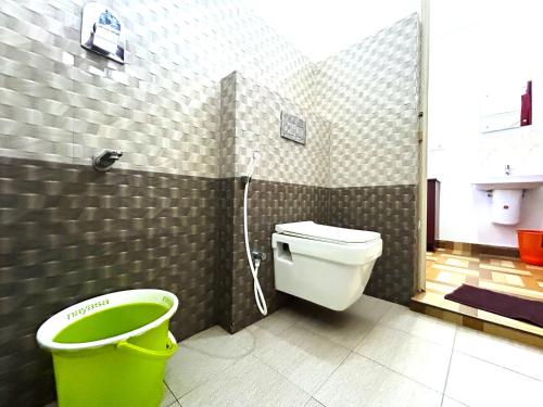 a bathroom with a toilet and a green bucket at Deluxe Residency in Kalpetta
