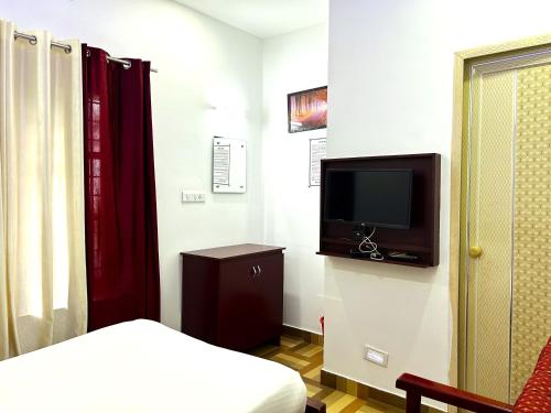 a room with a bed and a tv on a wall at Deluxe Residency in Kalpetta