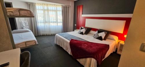 Habitación de hotel con cama con cabecero rojo en Hotel Spa El Muelle de Suances, en Suances