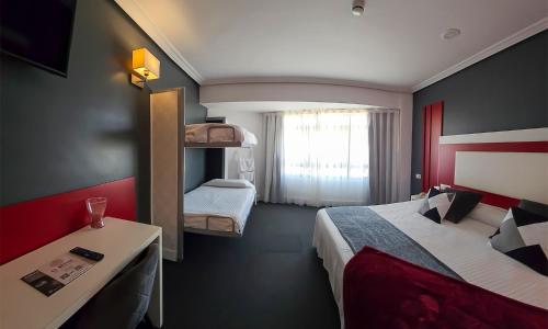 スアンセスにあるHotel Spa El Muelle de Suancesのベッド2台、デスク、ベッド1台が備わる小さな客室です。
