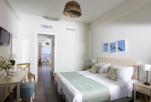 a white bedroom with a bed and a desk at Artina Nuovo in Marathopolis