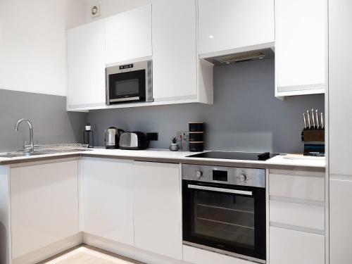 a white kitchen with white cabinets and a microwave at Apartment in Brighton in Brighton & Hove