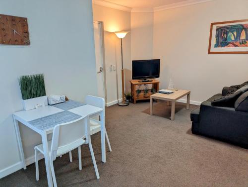 a living room with a white table and a couch at Kings Park Oasis with private courtyard, pool, free secure allocated parking and gym in Perth