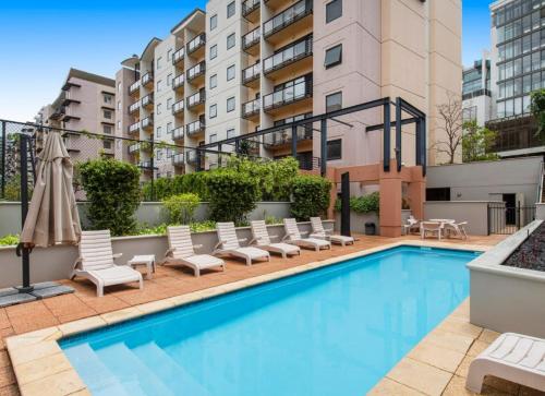 a swimming pool with lounge chairs and a building at Kings Park Oasis with private courtyard, pool, free secure allocated parking and gym in Perth