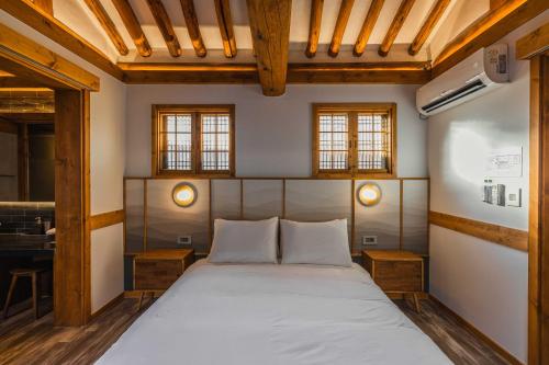 a bedroom with a bed with two tables and two windows at Luxury hanok with private bathtub - SN04 in Seoul
