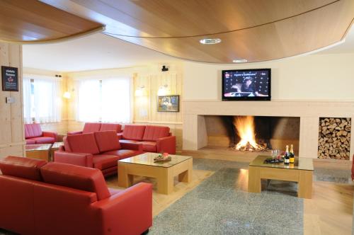 a living room with red chairs and a fireplace at Hotel Garni Pegrà in Ponte di Legno