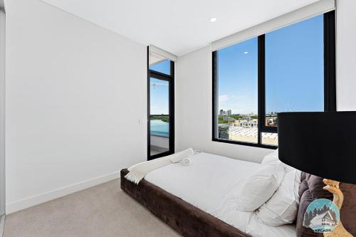 a bedroom with a bed and large windows at Aircabin｜Wentworth Point｜Stylish Comfy｜2 Beds Apt in Sydney