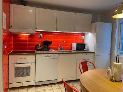 una cocina con armarios blancos y azulejos rojos en Ferienwohnung für 5 Personen ca 60 qm in Borlänge, Mittelschweden See Runn en Borlänge