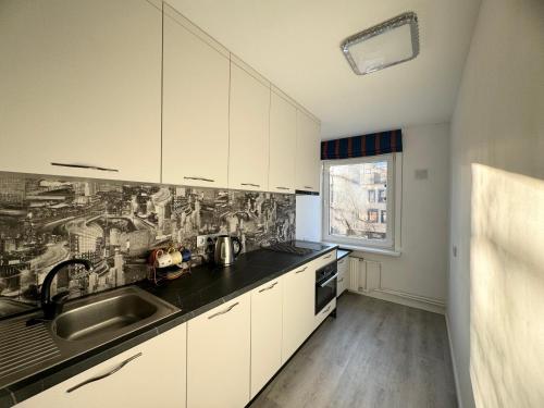 una cocina con armarios blancos y fregadero en Quiet, well located, Riga Apartment, en Riga