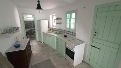 a kitchen with green cabinets and a white refrigerator at Παραδοσιακό Σπίτι στον Πύργο in Panormos