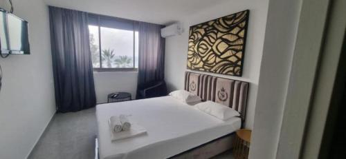 1 dormitorio con cama blanca y ventana en Elis Boutique Hotel, en Bat Yam