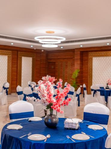 a room with blue tables and white chairs and a vase with flowers at Playotel Resort Bhopal in Bhopal
