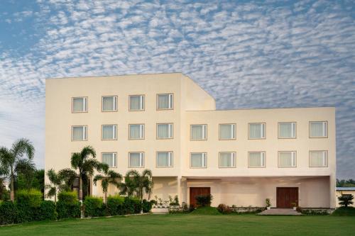 een groot wit gebouw met palmbomen en een bewolkte hemel bij Playotel Resort Bhopal in Bhopal