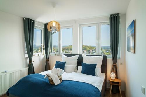 a bedroom with a blue and white bed with windows at Immo-Vision - Penthouse Privat Wellness in Bergneustadt