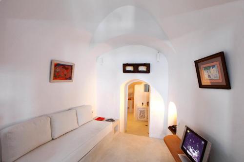 a living room with a white couch and a tv at Menias Cave House in Oia