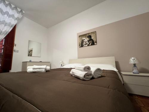1 dormitorio con 1 cama grande y toallas. en LA ROSA DEI VENTI en Villafranca Tirrena