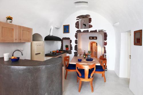 a kitchen and dining room with a table and chairs at Menias Cave House in Oia