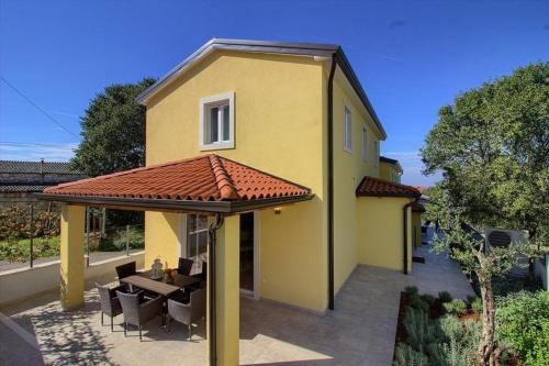 una casa amarilla con mesa y techo en Ferienhaus mit Privatpool für 8 Personen ca 120 qm in Mugeba, Istrien Istrische Riviera, en Mugeba