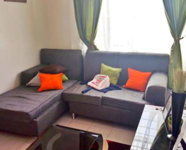 a living room with a blue couch with colorful pillows at Legacy Stays in Kikuyu