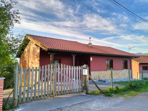 a red house with a wooden fence in front of it at La Casa de Nuria in Cangas de Onís