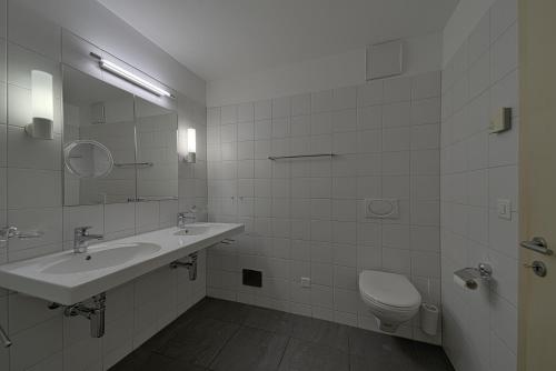 a white bathroom with a sink and a toilet at Chesa Rivarel - Pontresina in Pontresina