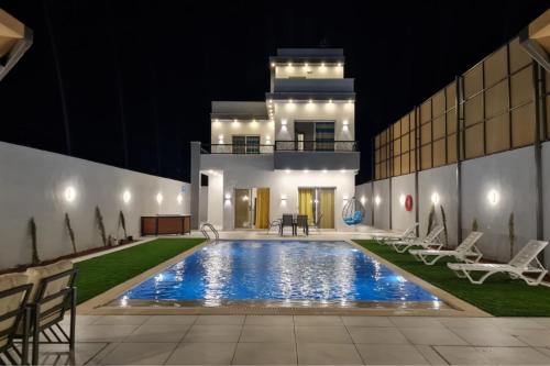 a villa with a swimming pool at night at Jimi Chalet in Al Kafrayn