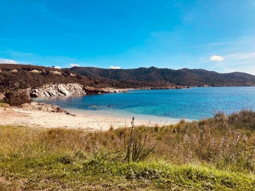 a beach with blue water and mountains in the background at Domu in su satu in Masainas