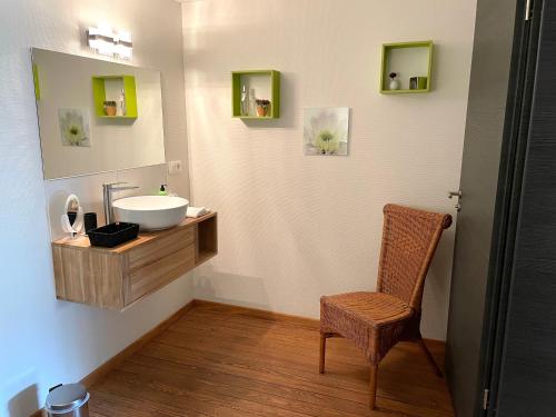 a bathroom with a sink and a chair at Les Myosotis Chambres d'hôtes - Sarreguemines in Zetting