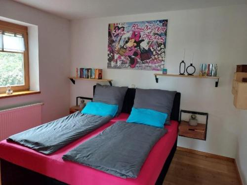 a bedroom with a pink bed with blue pillows at Kuckucksnest - Ferienwohnung Welschneudorf in Welschneudorf