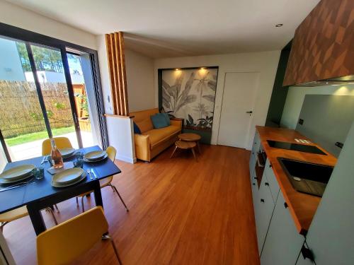 uma cozinha e sala de estar com uma mesa e um sofá em Brand new surf lodge at the end of golf em Soorts-Hossegor