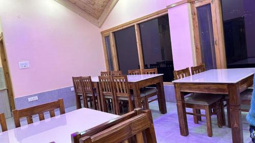 uma sala de jantar com mesas e cadeiras de madeira em The Exotic Retreat em Manali