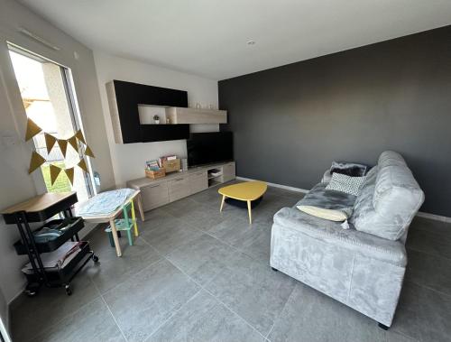 uma sala de estar com um sofá e uma televisão em Chambres 24h du Mans em Mulsanne