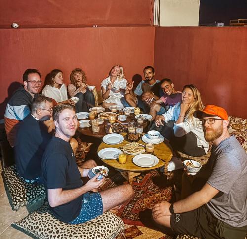 un grupo de personas sentadas alrededor de una mesa comiendo en Olympe Surf & Yoga en Tamraght Ouzdar