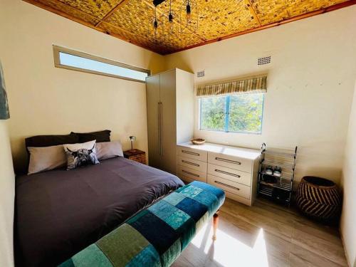 a bedroom with a large bed and a window at Charming Cottage in the wilderness on 5 Acres in Lusaka