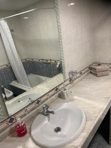 a bathroom with a sink and a mirror and a tub at APARTAMENTO AUGAS DO COIDO in Muxia