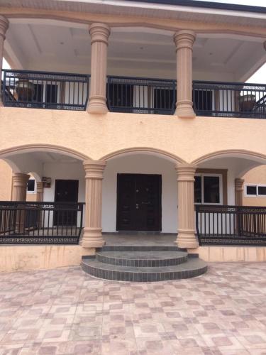 un edificio con columnas y escaleras en un patio en Estben guesthouse, en Kwabenyan