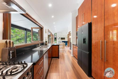 a kitchen with wooden cabinets and a black refrigerator at Aircabin - Warrawee - Sydney - 5 Beds House in Warrawee