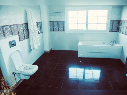een badkamer met een bad, een toilet en een raam bij HOTEL MOUNIRA in Arzew