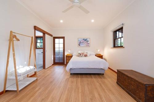 a large white bedroom with a bed and wooden floors at Blueberry Farm Cottage in Willunga