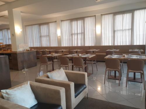 uma sala de jantar com mesas, cadeiras e janelas em Hotel Bianca Vela em Rimini