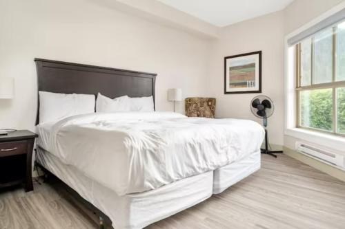 a white bedroom with a large bed and a window at Lakeview Splendor- 7BR Penthouse Bliss Combo unit in Harrison Hot Springs