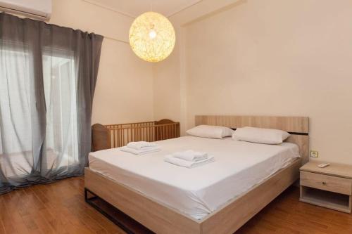a bedroom with a bed with white sheets and a chandelier at Luxury Pireas Stay New 2BR Urban Escape in Piraeus