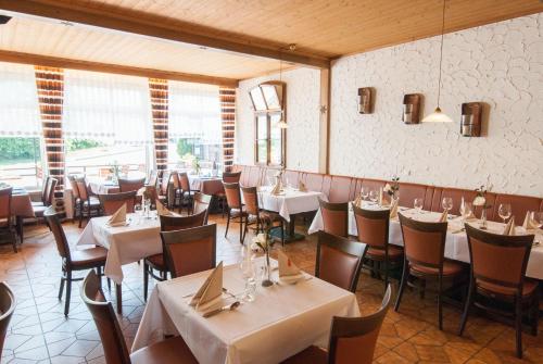 a restaurant with white tables and chairs and windows at Gasthaus Hotel Pfeifferling in Wolfhagen