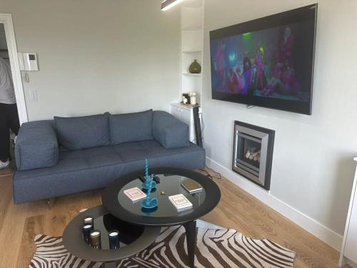 a living room with a couch and a tv on a wall at Abbey Road Luxury Modern Flat w Historic Vibes in London